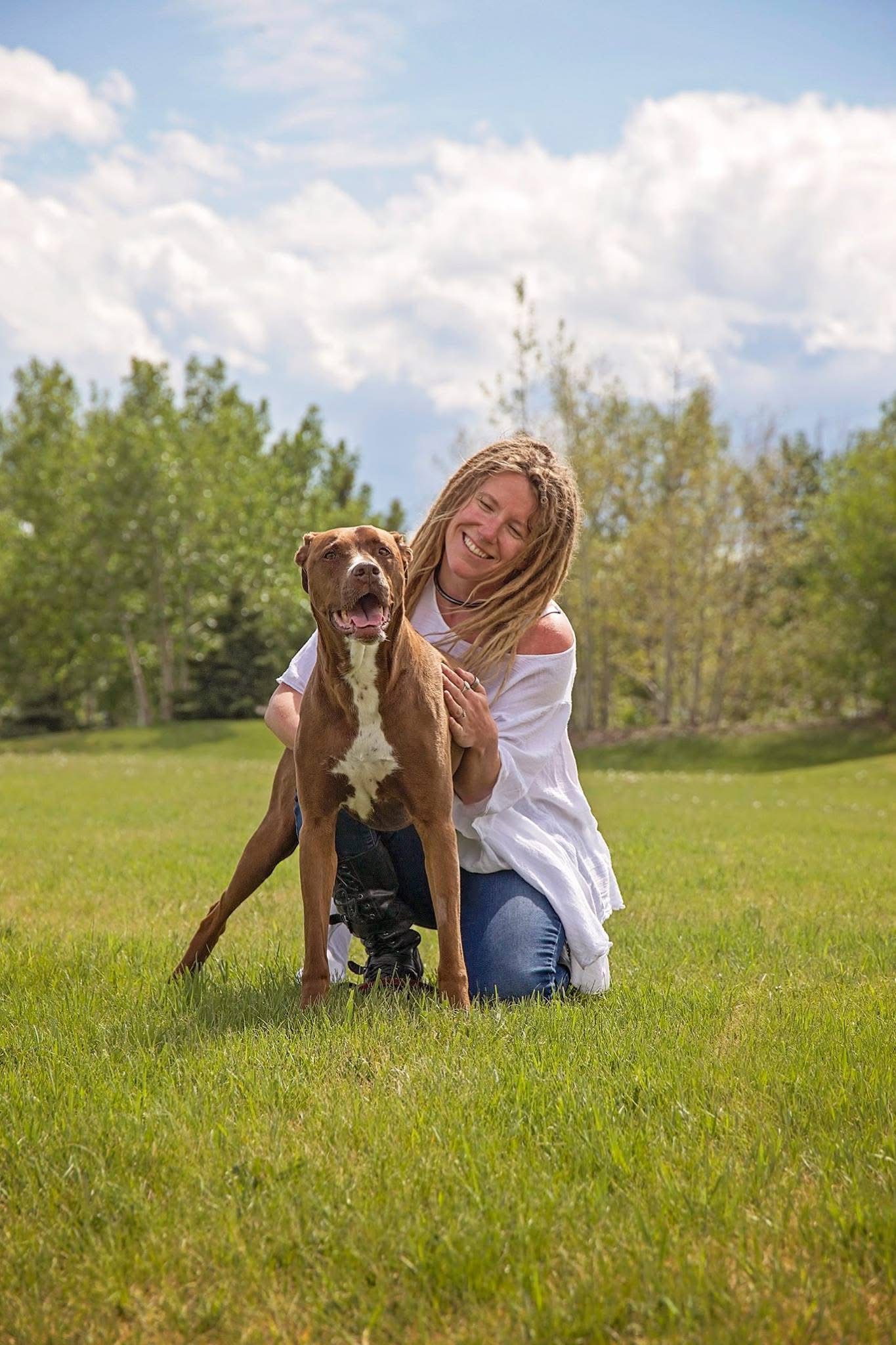 Girl snuggles brown dog in a green park